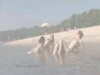Një publike plazh heats lart me dy nxehtë kukulla nudists